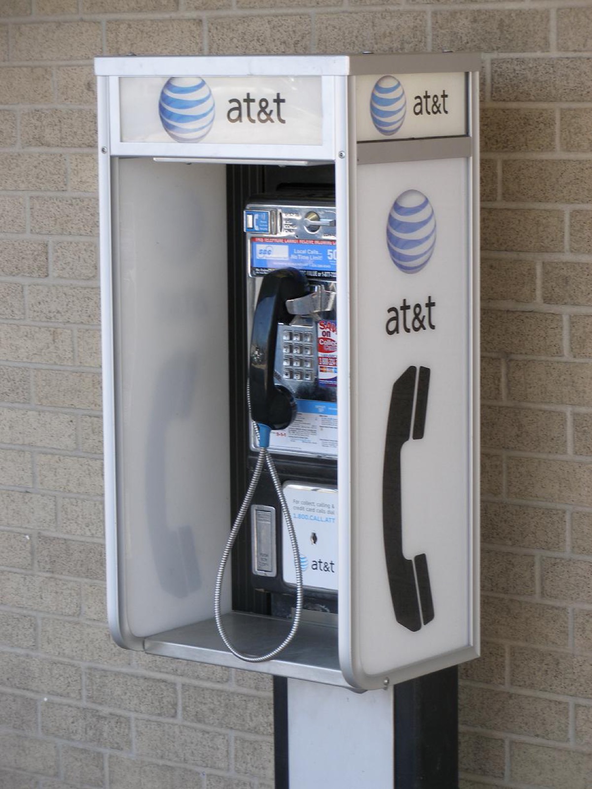AT&T-branded outdoor payphone booth mounted against a brick wall